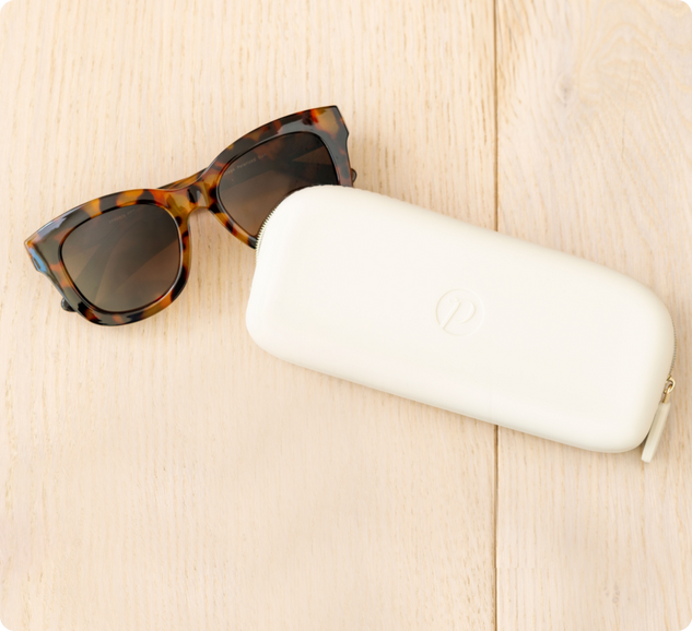 sunglasses and white eyewear case laying flat on the ground 