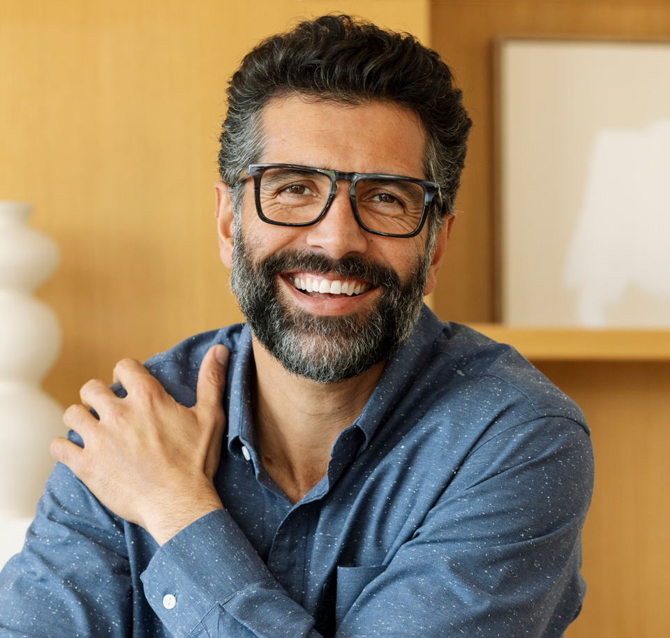 Man wearing black reading glasses smiling 