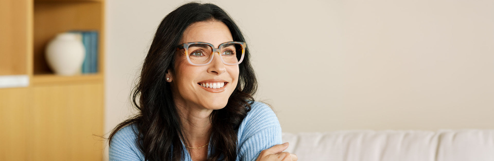 Main hero: women wearing pink and brown reading glasses sitting on a couch