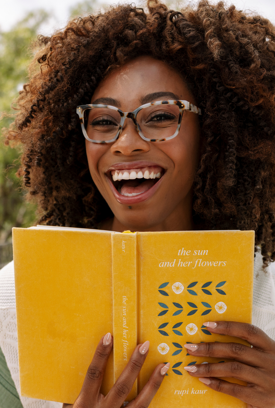 Model wearing reading glasses holding a book