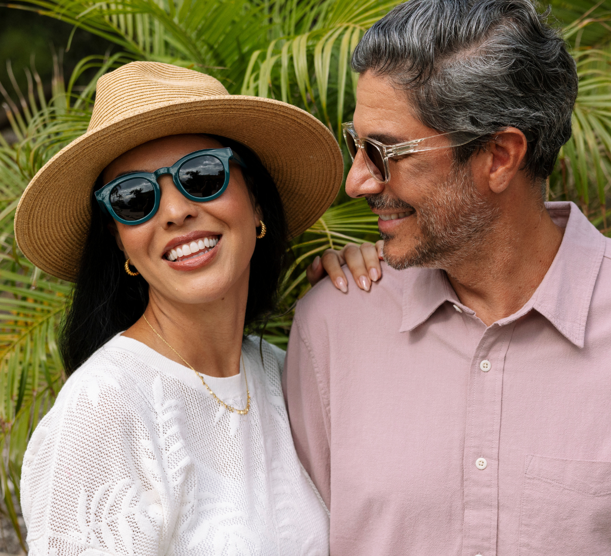 Man and women wearing sunglasses smiling outside