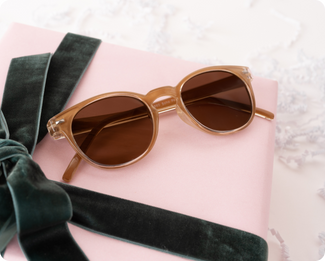 Amber sunglasses sitting on a pink present with green ribbon