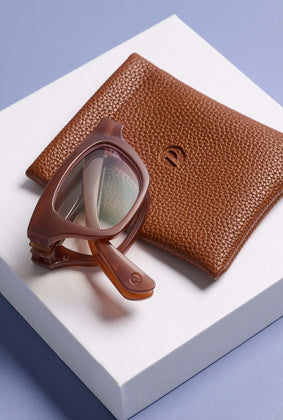 brown twofold reading glasses with leather case with a white and purple background